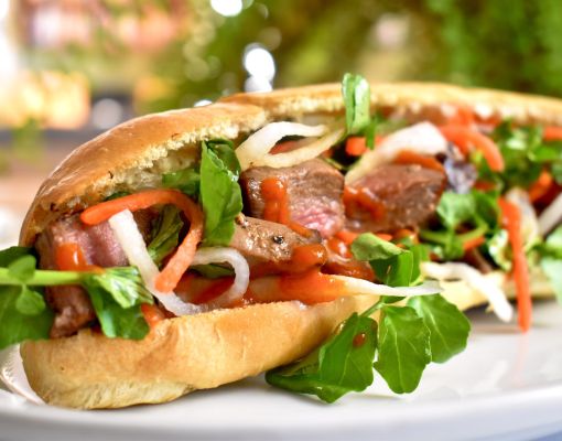 Delicious venison sandwich layered with fresh greens and sauce.