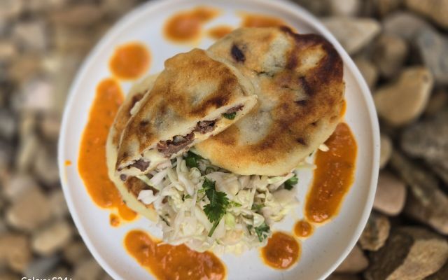 Delicious pupusa served with salad and sauce on a plate.